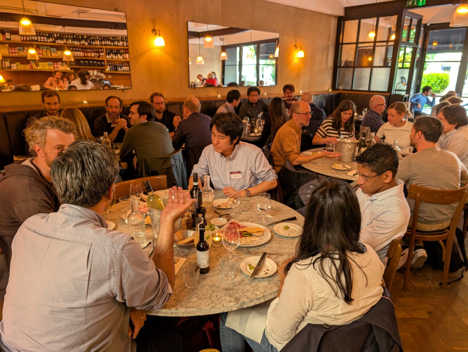 Participants of the BÆM 2025 development economics workshop talking over dinner at round tables in a restaurant