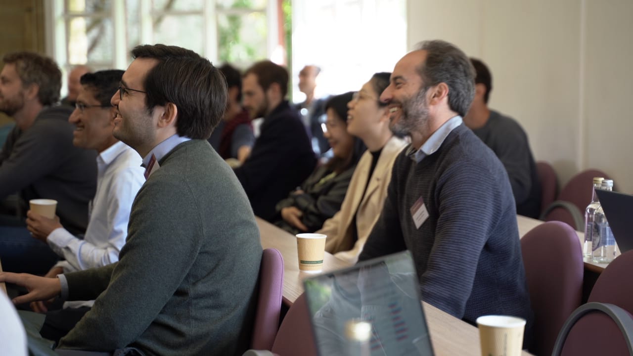 Participants of the BÆM 2025 development economics workshop smiling and laughing while listening to a talk